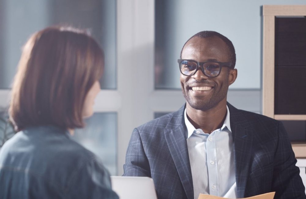 a man in a suit and glasses smiling at a woman